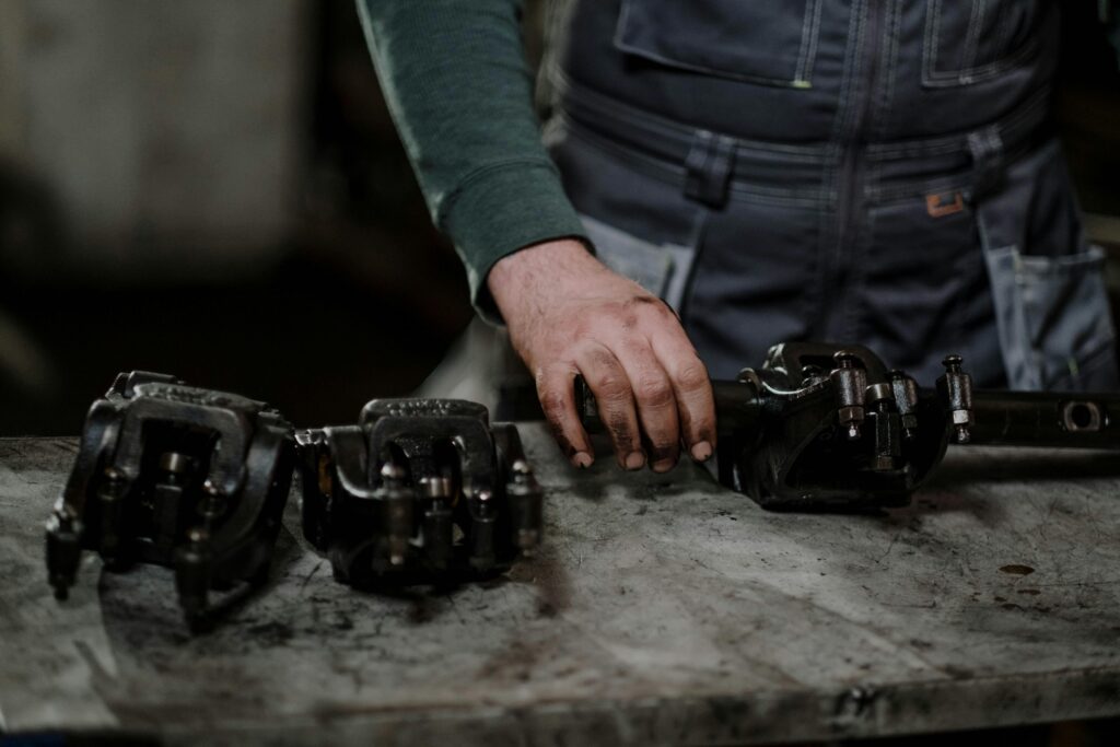 Mechanic in workshop handling greasy metal parts on workbench, depicting repair process.